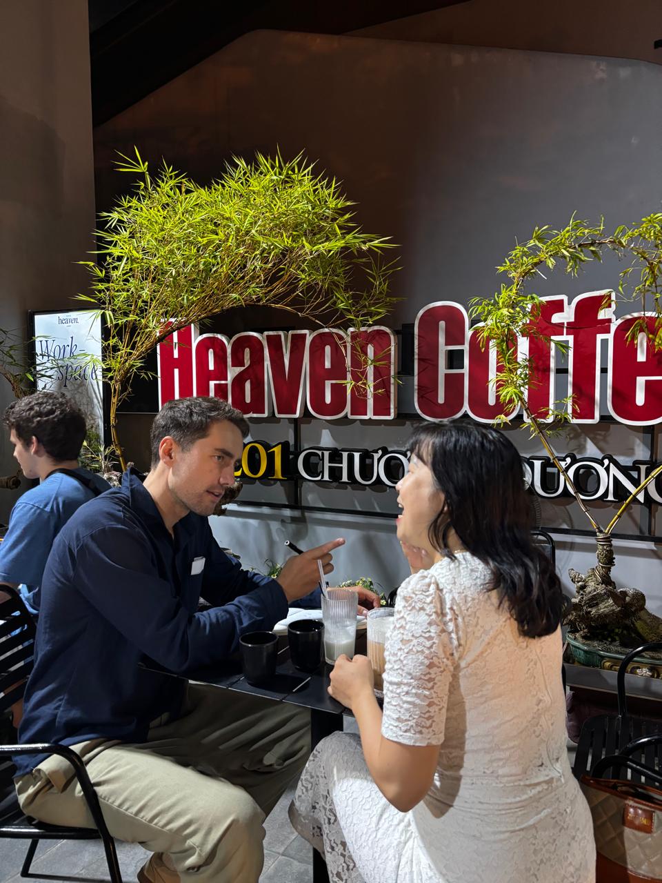 A focused conversation beside the Heaven Coffee sign during the Friday, May 1, 2026 language exchange meetup.